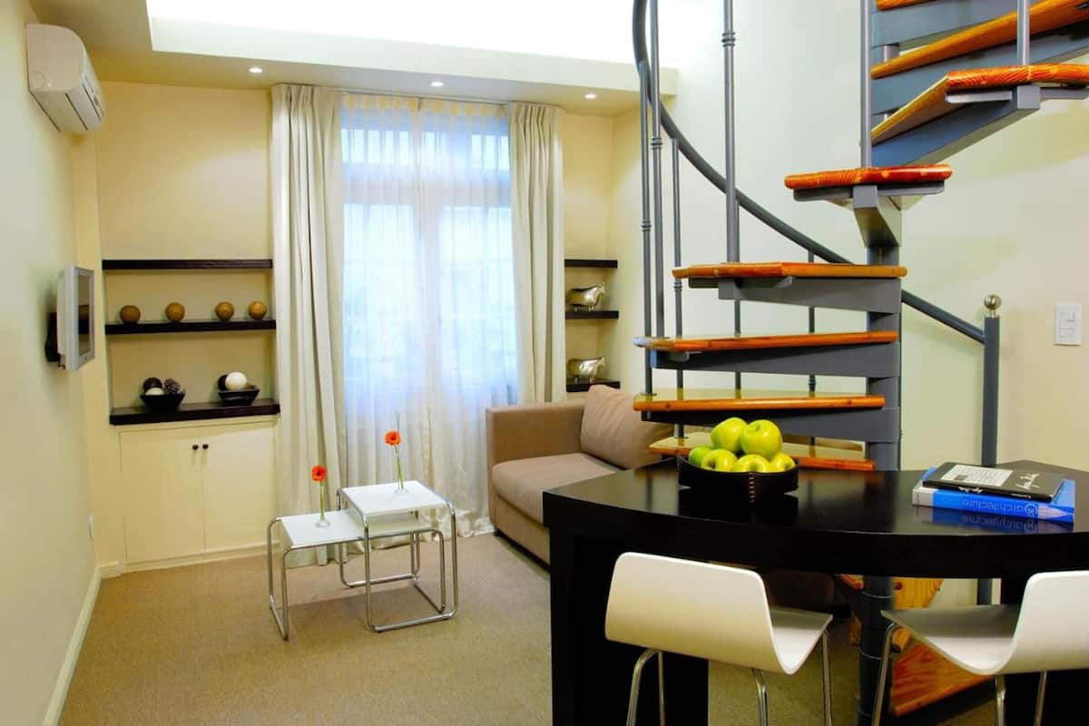 Una sala de estar moderna con una escalera, un comedor y un sofá.