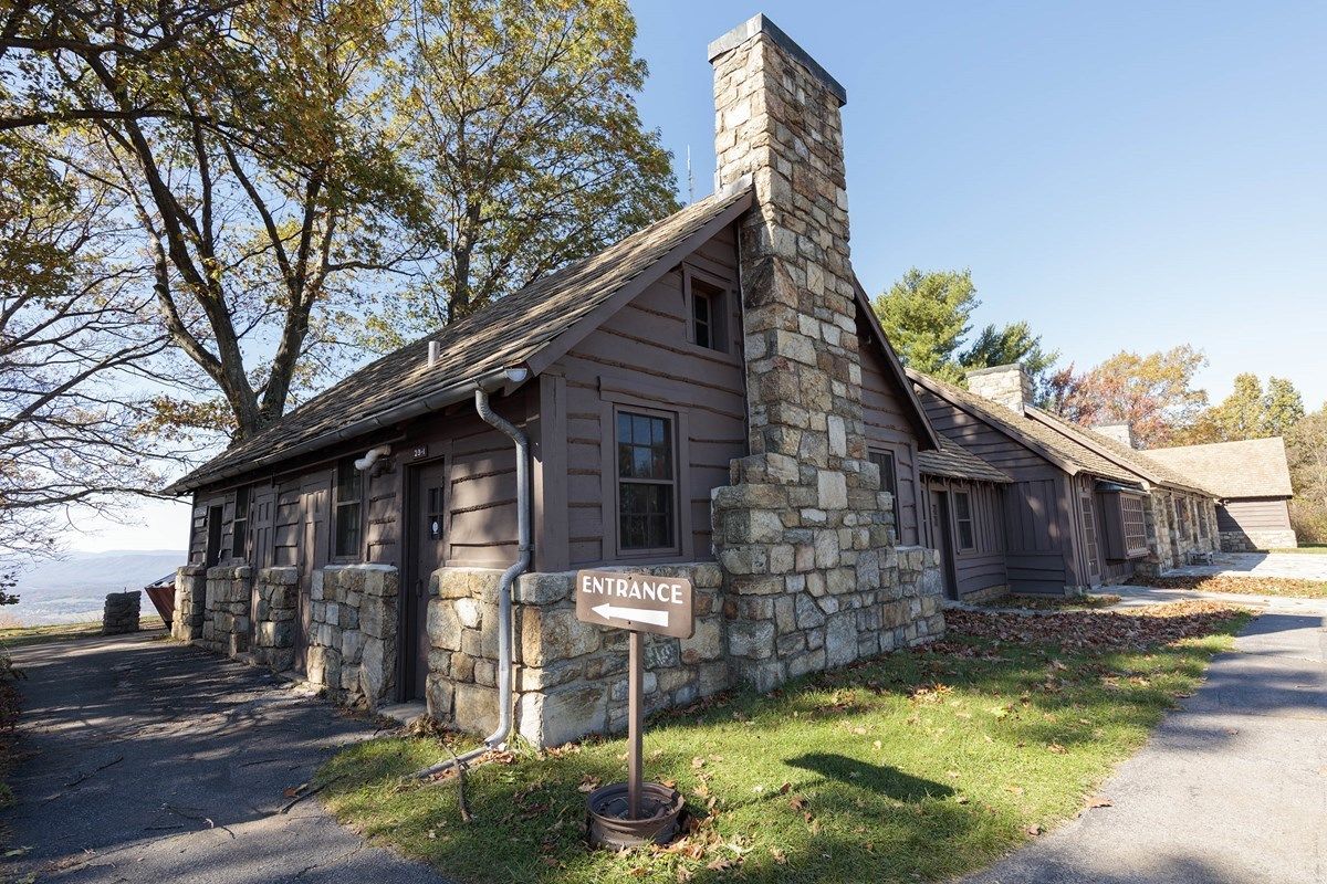 A rustic stone building with a chimney, an entrance sign, and a clear view of the surrounding landscape.