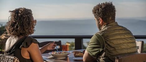 Two people dining at an outdoor table with a scenic view.