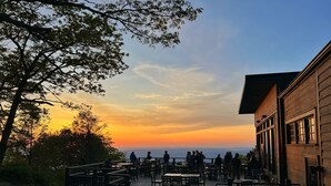 An outdoor seating area with tables and chairs, overlooking a sunset view. - Skyland (Luray)