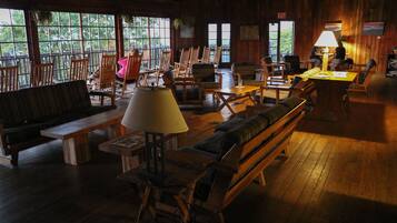 A cozy, rustic interior with wooden furniture, large windows, and a warm ambiance.