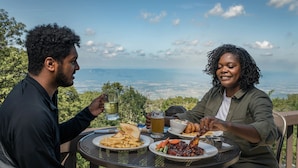 Two people dining at an outdoor table with a scenic view.