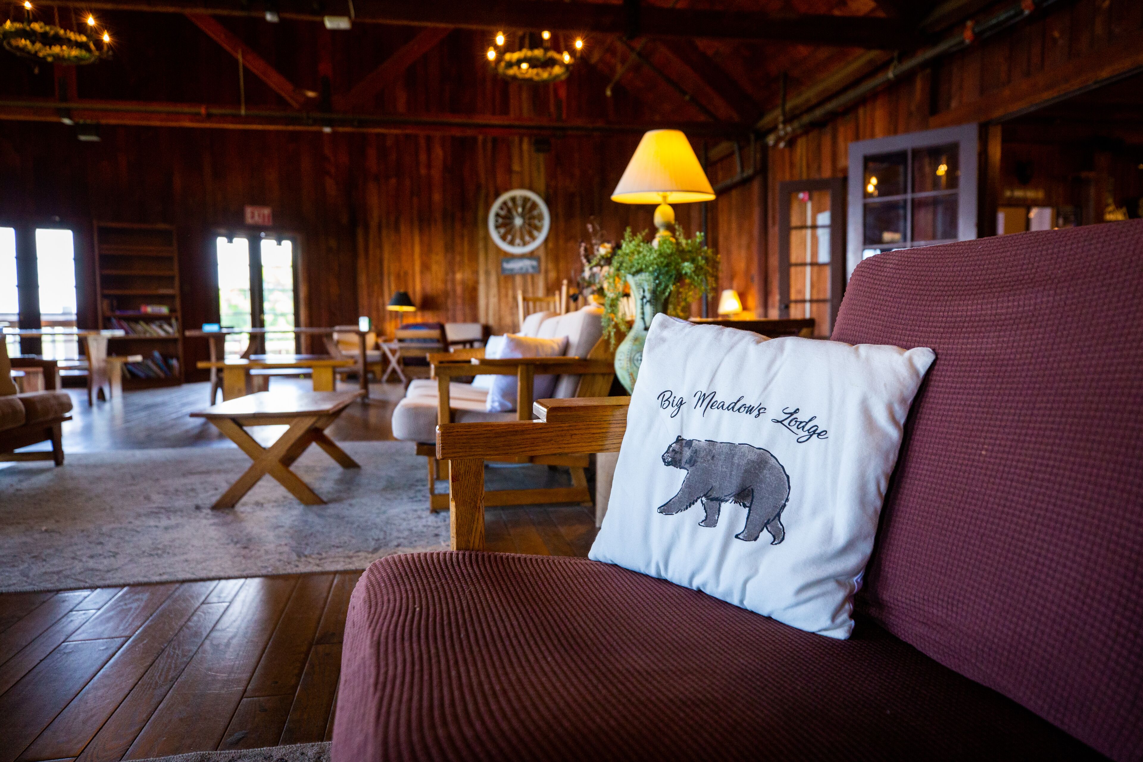 Ein gemütliches Lodge-Interieur mit Holzmöbeln, einem Bär-Kissen und einem großen Fenster.