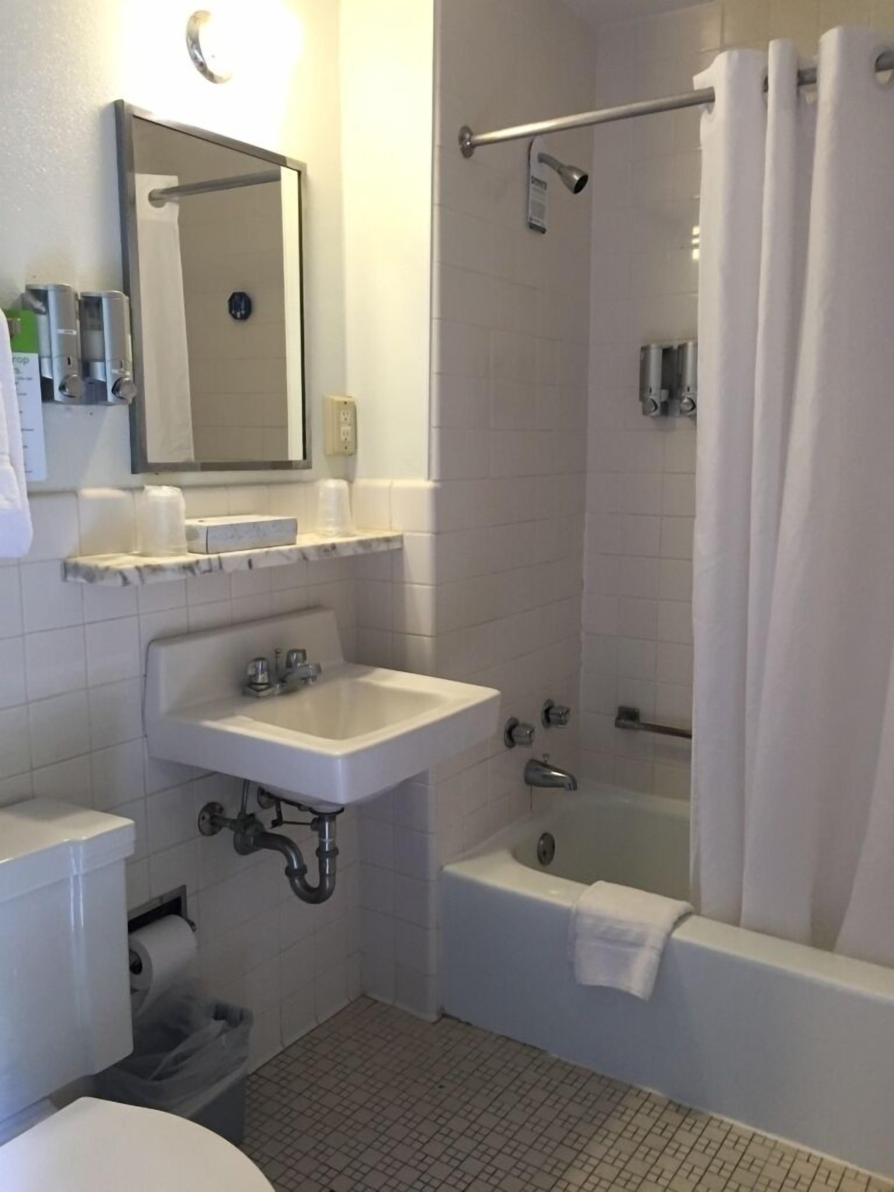 A standard bathroom with a sink, mirror, toilet, and shower area.