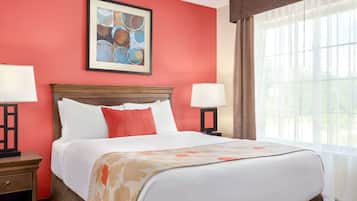 A hotel room with a large bed, two bedside tables, a framed artwork above the bed, and a window with curtains.