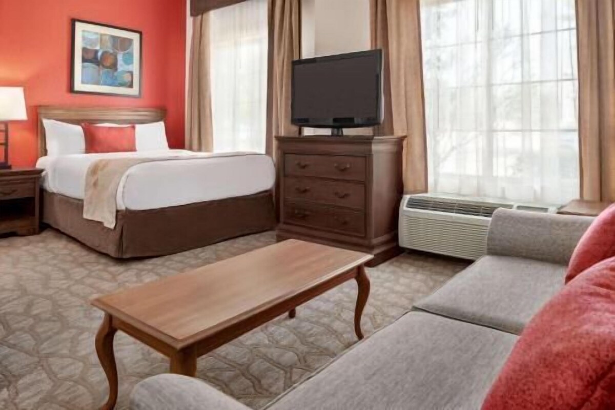 A hotel room with a bed, a television, a dresser, a sofa, and a coffee table.