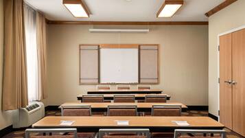 A conference room with a whiteboard, tables, and chairs.