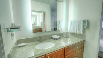 Baño con encimera de granito, lavamanos blanco y armarios de madera.