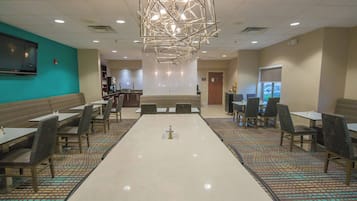 A spacious dining area with a long table, multiple chairs, and a modern chandelier.