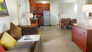 A compact living space with a kitchenette, a dining area, and a seating area with a sofa and a table.