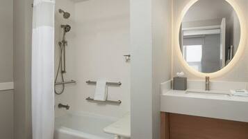 A modern bathroom with a bathtub, shower, and a vanity with a mirror.