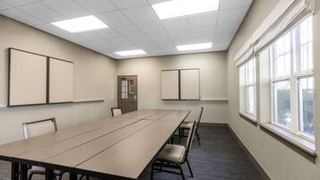 A conference room with a long table, chairs, a door, and windows.