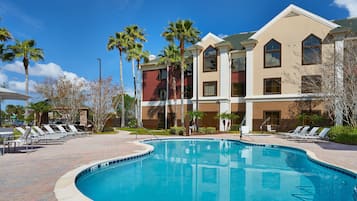 Una piscina al aire libre, sillones reclinables de piscina