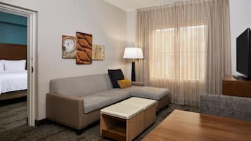Een hotelkamer met een bed, een bank, een kleine tafel, een lamp en een televisie.