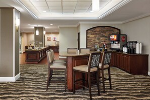 Un hall de hotel con zona de bar, asientos y una pared de acento de piedra.