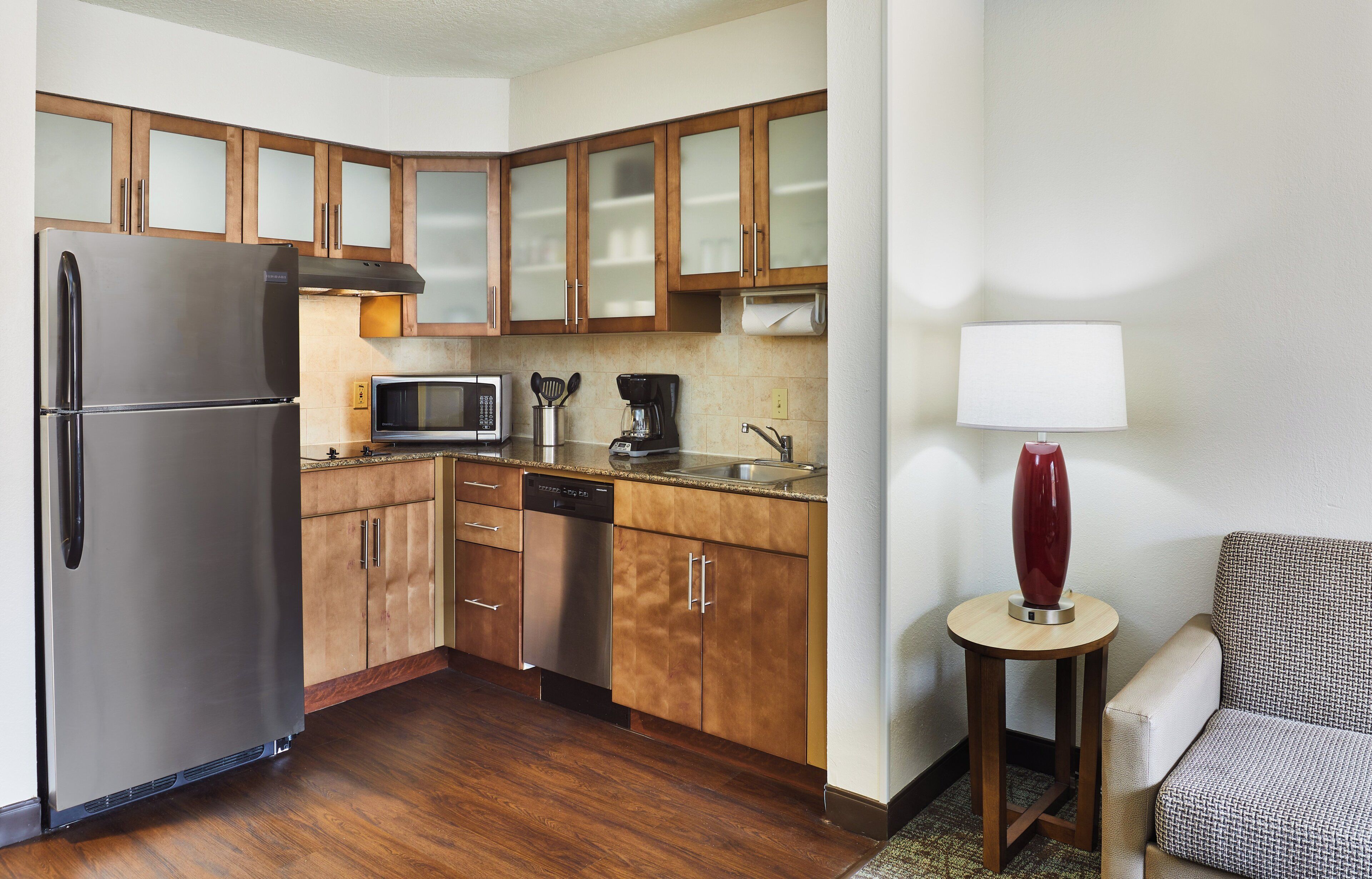A compact kitchen with a refrigerator, microwave, coffee maker, and dishwasher.
