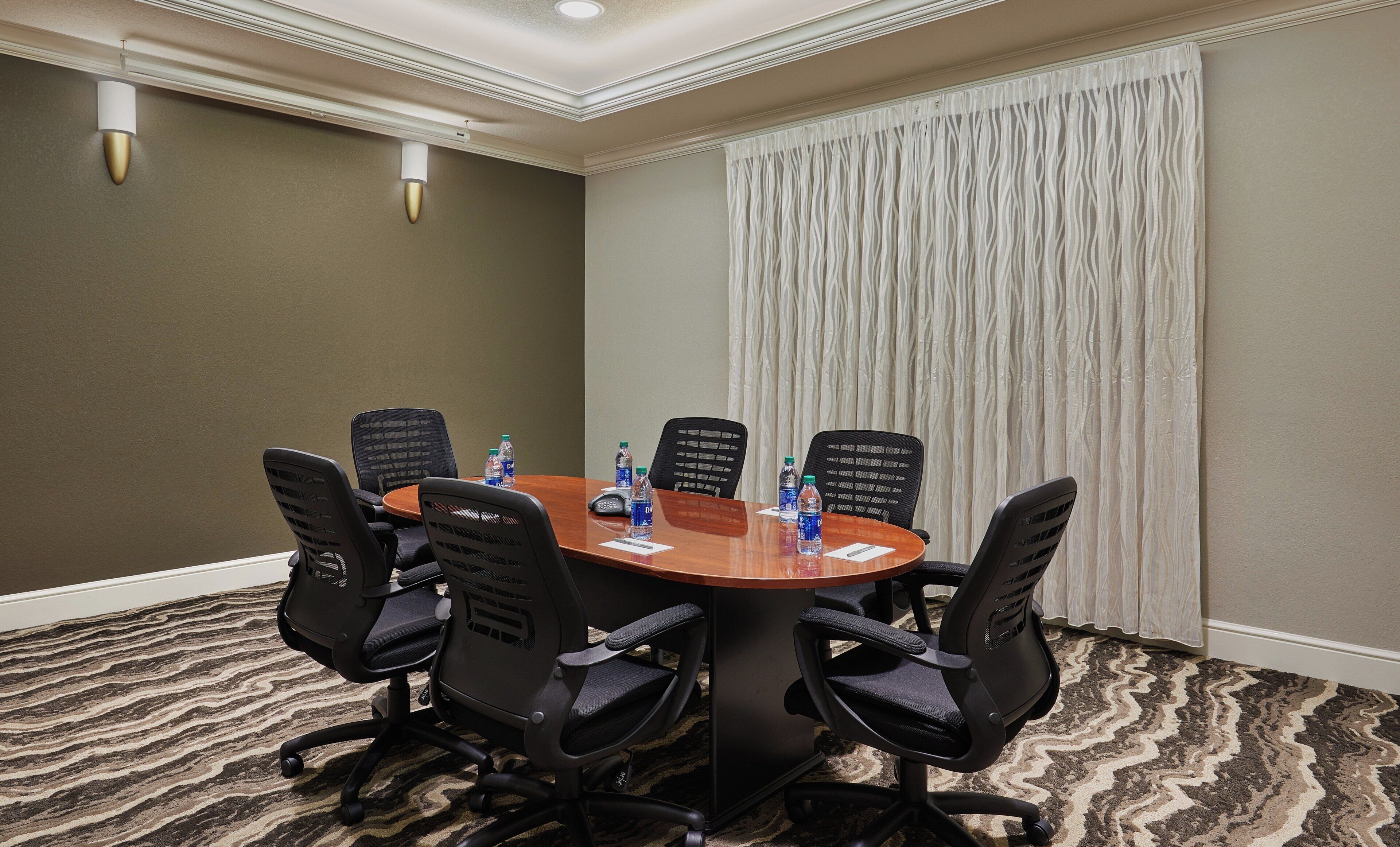 A conference room with a round table, six chairs, and water bottles on the table.