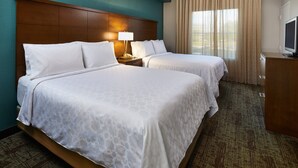 A hotel room with two beds, a wooden headboard, a TV, and a window with curtains. - Staybridge Suites Orlando Airport South by IHG (Orlando)