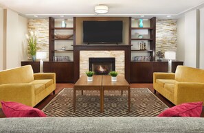 Una sala de estar moderna con chimenea, dos sillones, una mesa de centro y un televisor de pantalla plana montado sobre la chimenea.