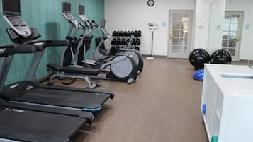 Un gimnasio con cintas de correr, bicicletas estáticas y pelotas de ejercicios.