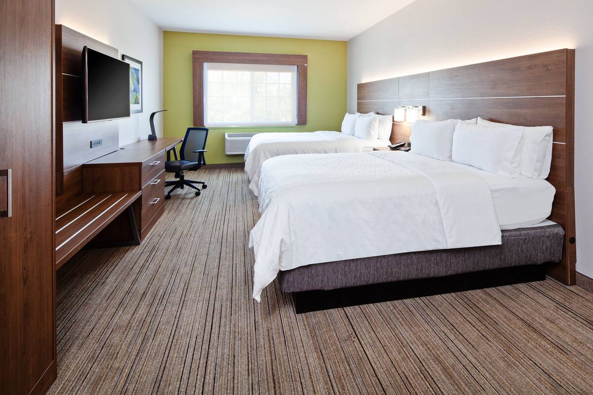 Une chambre d’hôtel avec deux lits, un bureau doté d’un téléviseur à écran plat, une chaise et une grande fenêtre.