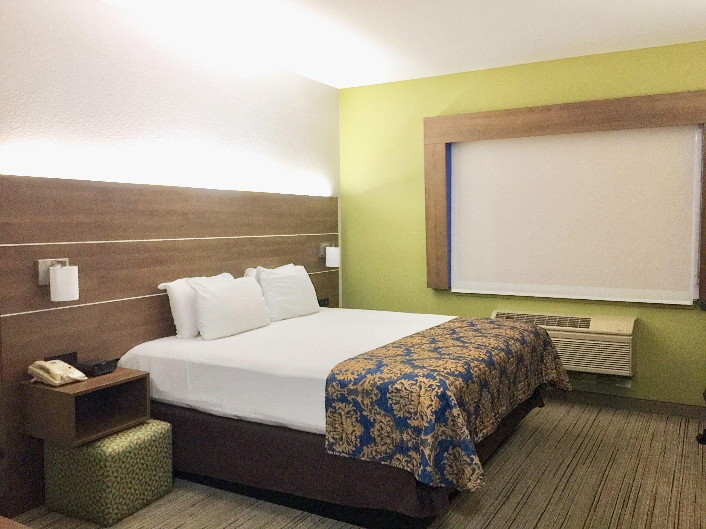 Une chambre d’hôtel équipée d’un lit, d’une table de chevet et d’un téléviseur fixé au mur.