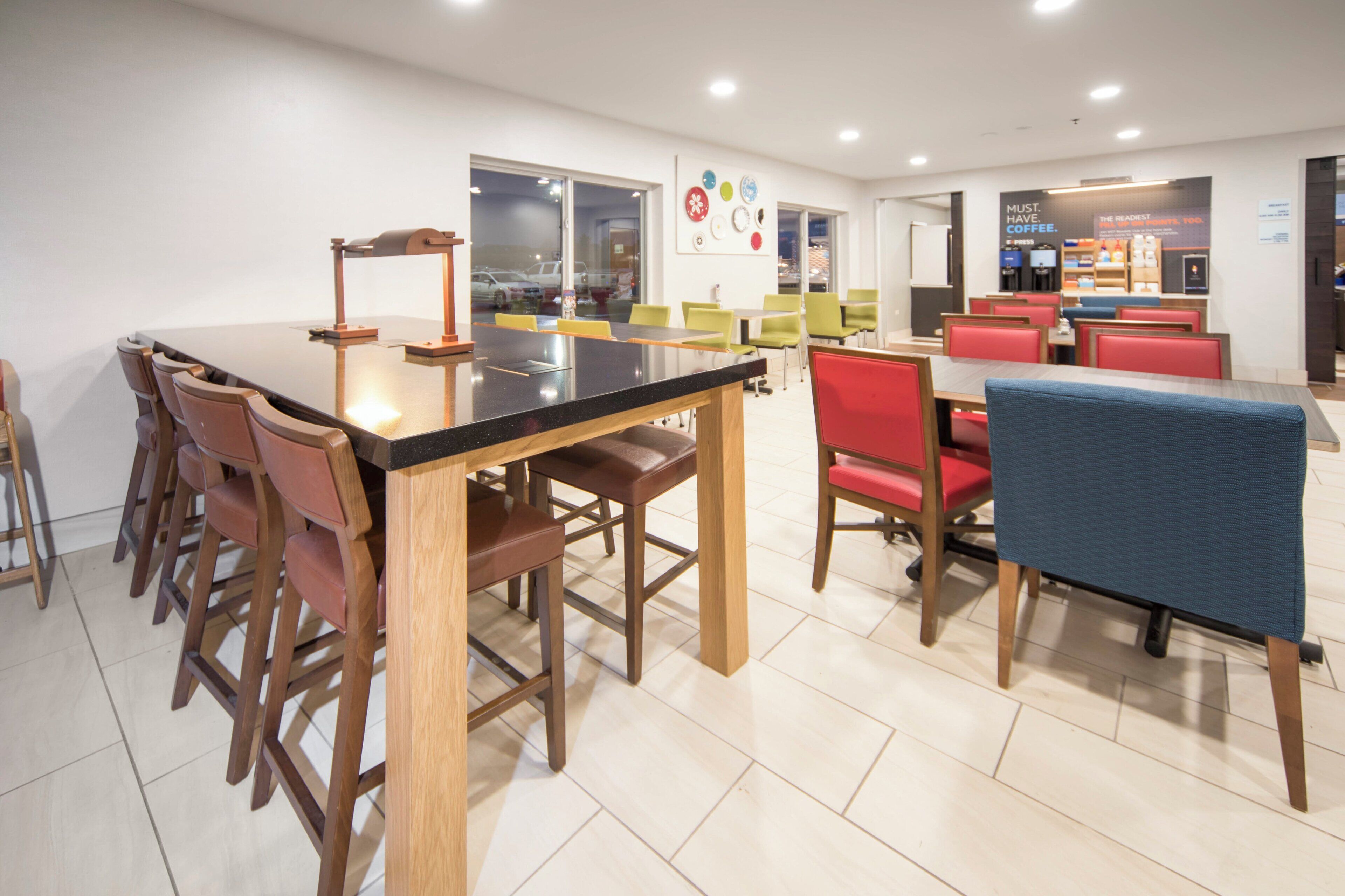 Un comedor moderno con una mesa larga y varias sillas, una estación de café y vistas por la ventana.
