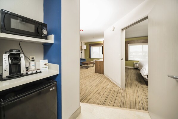 Une chambre d’hôtel équipée d’une kitchenette, d’un lit, d’une fenêtre et d’une porte donnant sur une autre pièce.