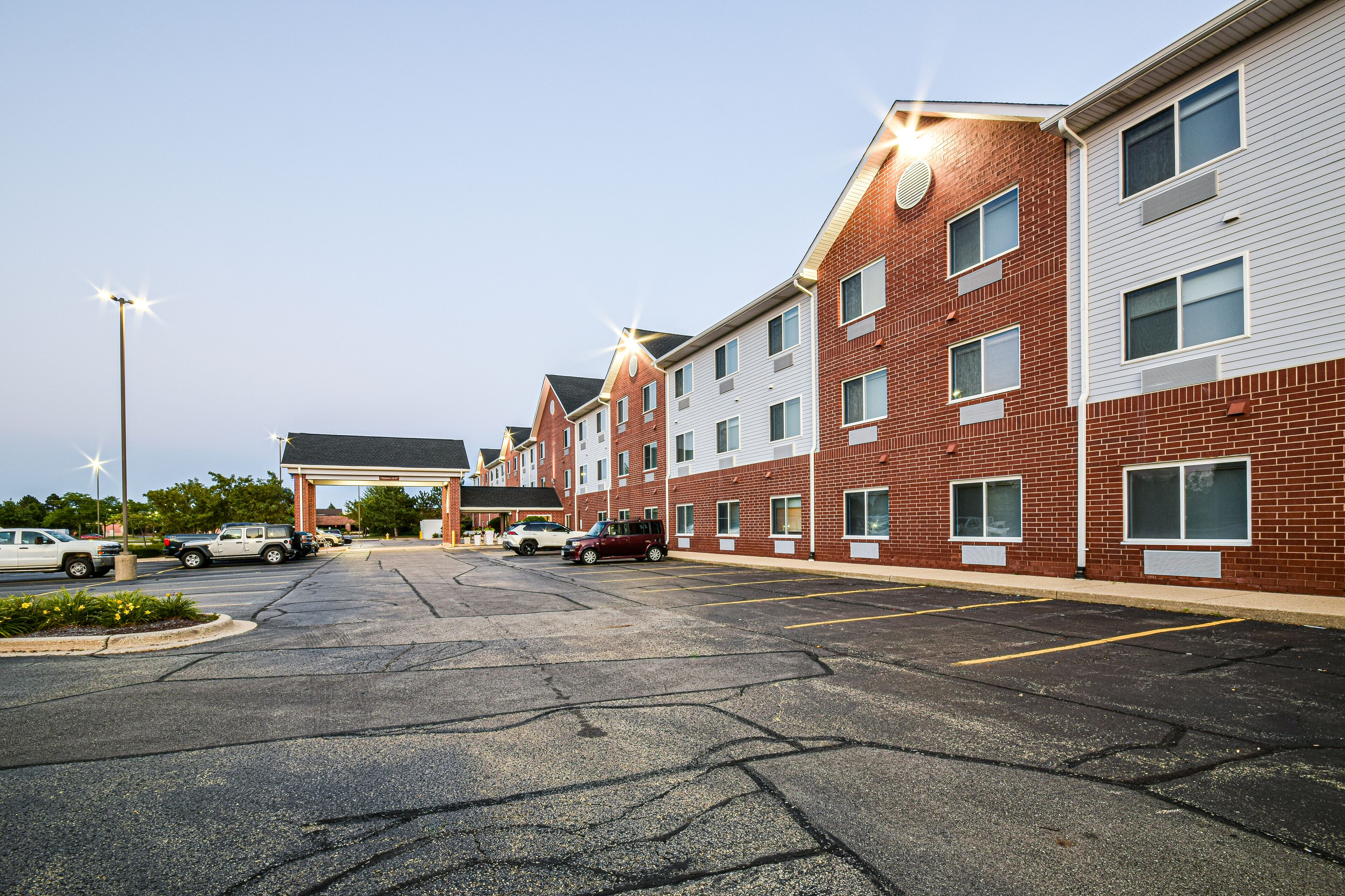 A multi-story hotel with a parking lot in front.