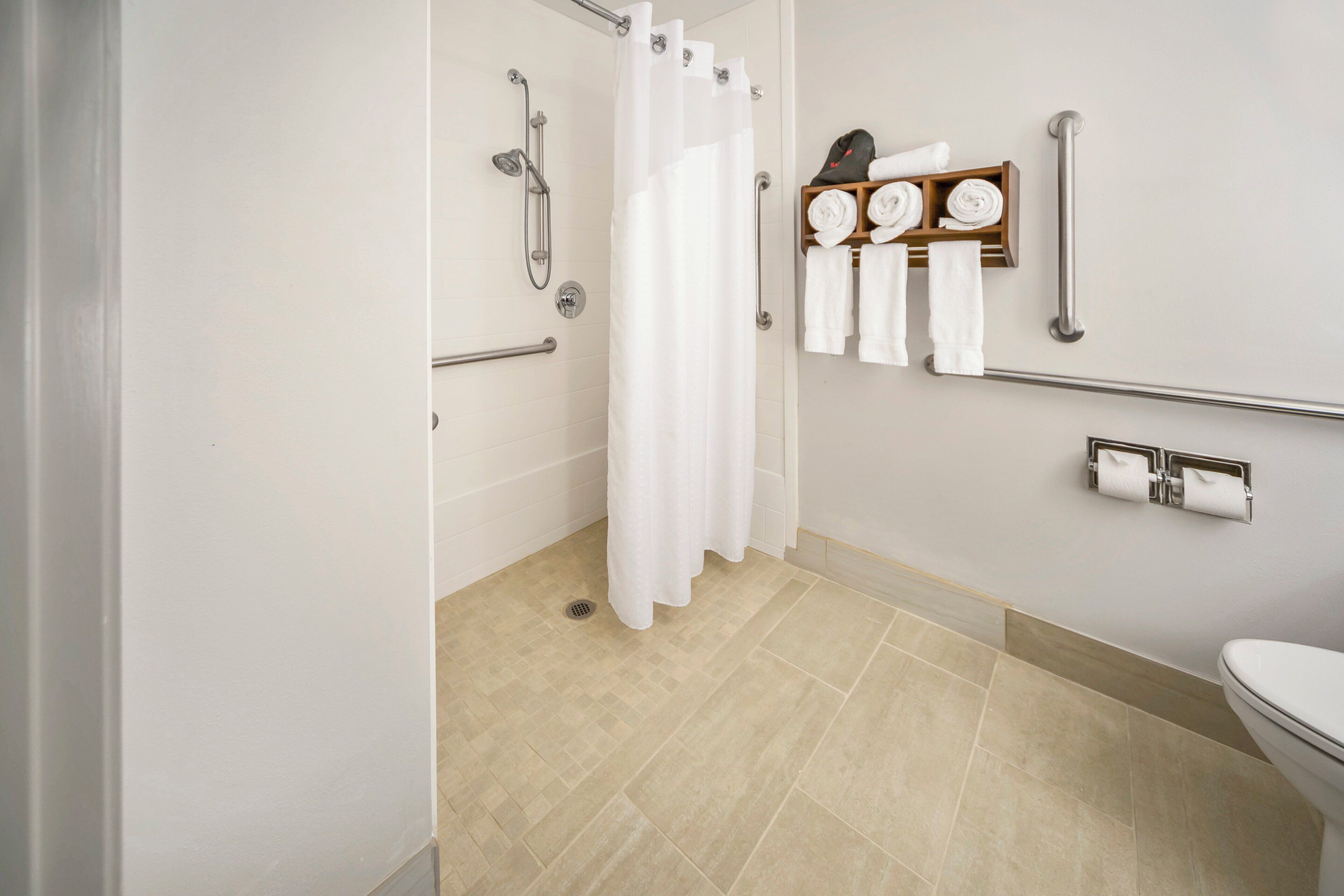 A bathroom with a shower, toilet, and towel rack.