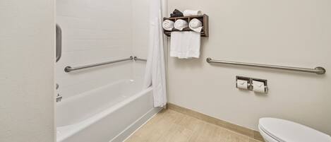 A bathroom with a white bathtub, a toilet, and a shower area.