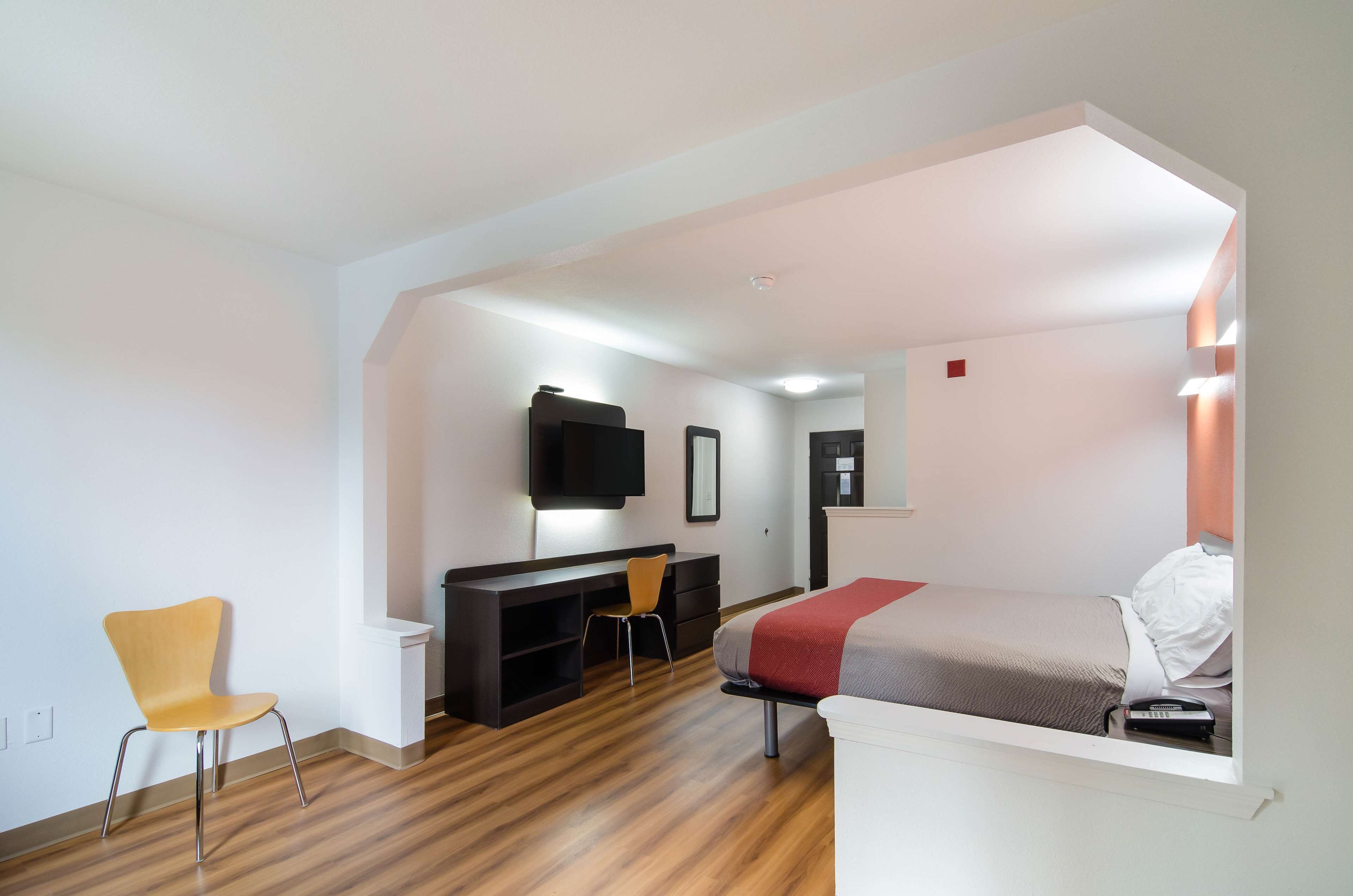 Een moderne kamer met een bed, bureau, stoel en televisie.