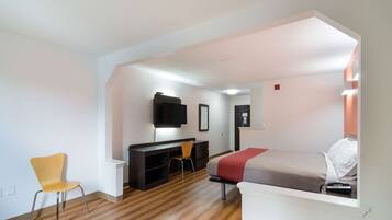 Een moderne kamer met een bed, bureau, stoel en televisie.