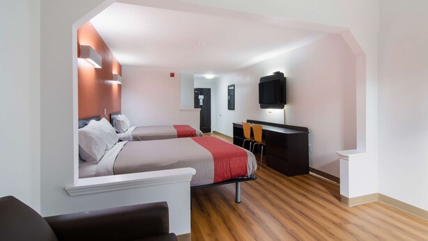 Una habitación de hotel moderna con dos camas, un escritorio y un televisor.