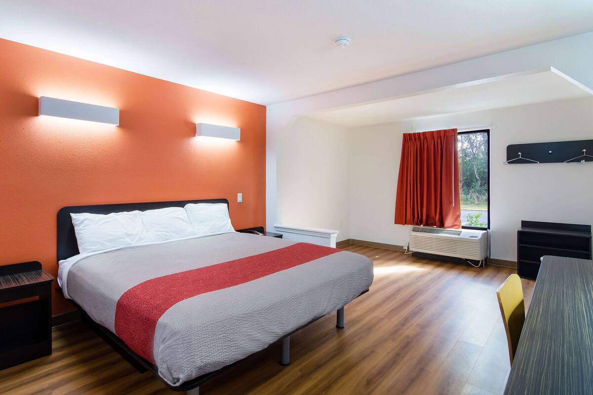 Ein modernes Hotelzimmer mit einem großen Bett, einem Schreibtisch und einem Vorhangfenster.