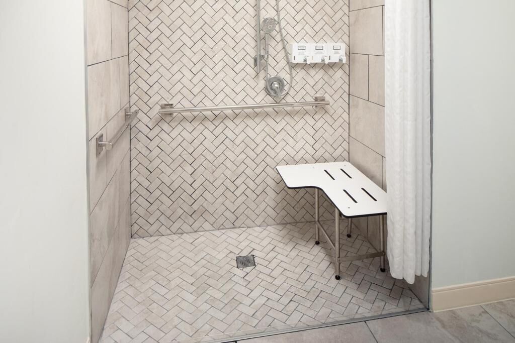 Chuveiro com padrão de azulejos em padrão herringbone, um porta-toalhas branco e um painel de controle do chuveiro.