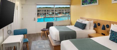 Habitación de hotel con dos camas, televisión, escritorio y vistas a una piscina y un edificio.