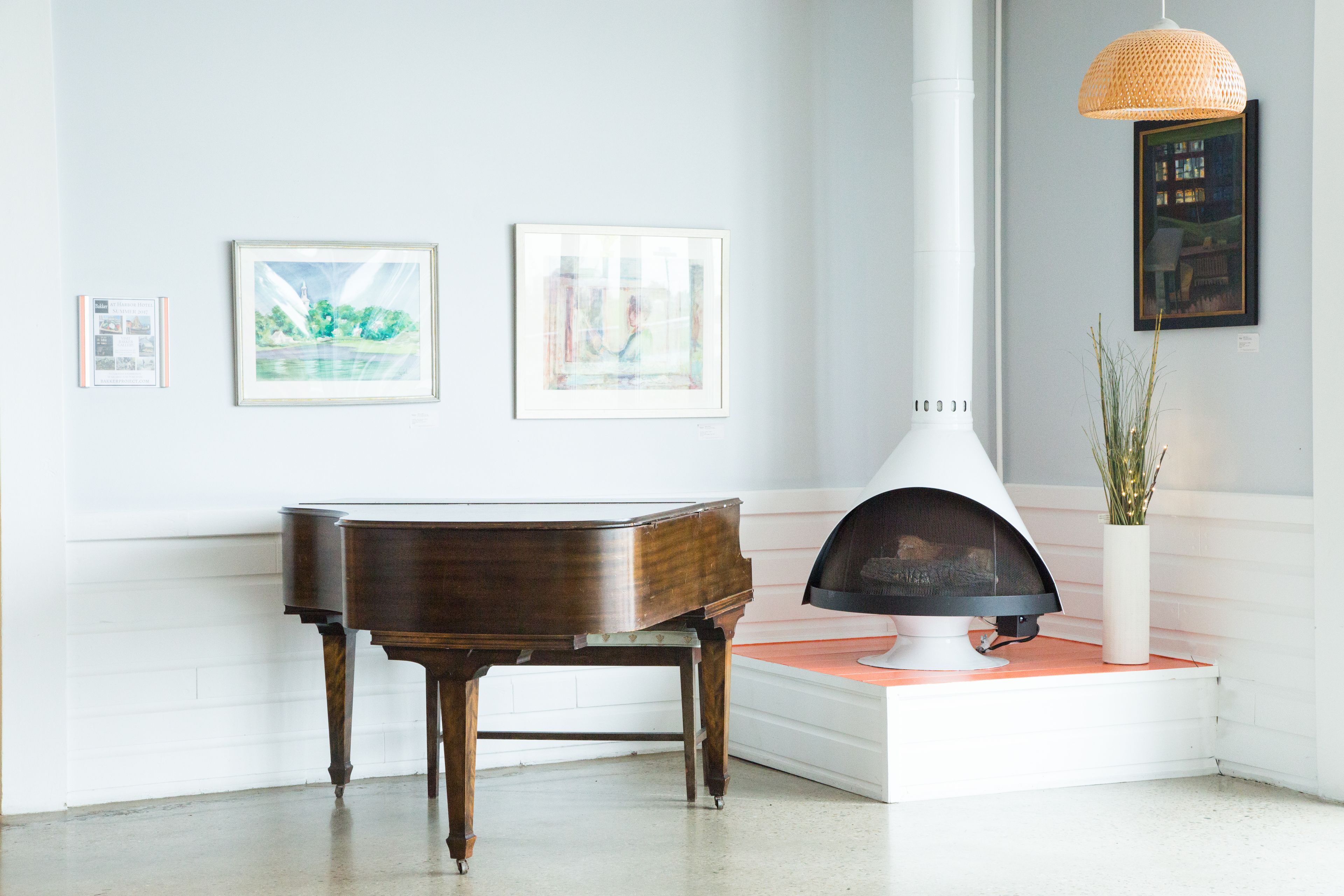 Un piano, una chimenea y obras de arte enmarcadas en una pared.