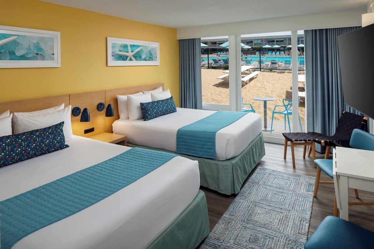 Une chambre d’hôtel avec deux lits, un bureau et une vue sur l’espace piscine.