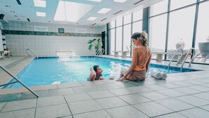 An indoor swimming pool with tiled walls, a lifeguard sign, and a view of the outside through large windows. - The Worthington Renaissance Fort Worth Hotel (Fort Worth)