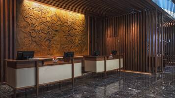 Zona de recepción con diseño moderno, que presenta un mostrador de madera y una pared decorativa con intrincados patrones.