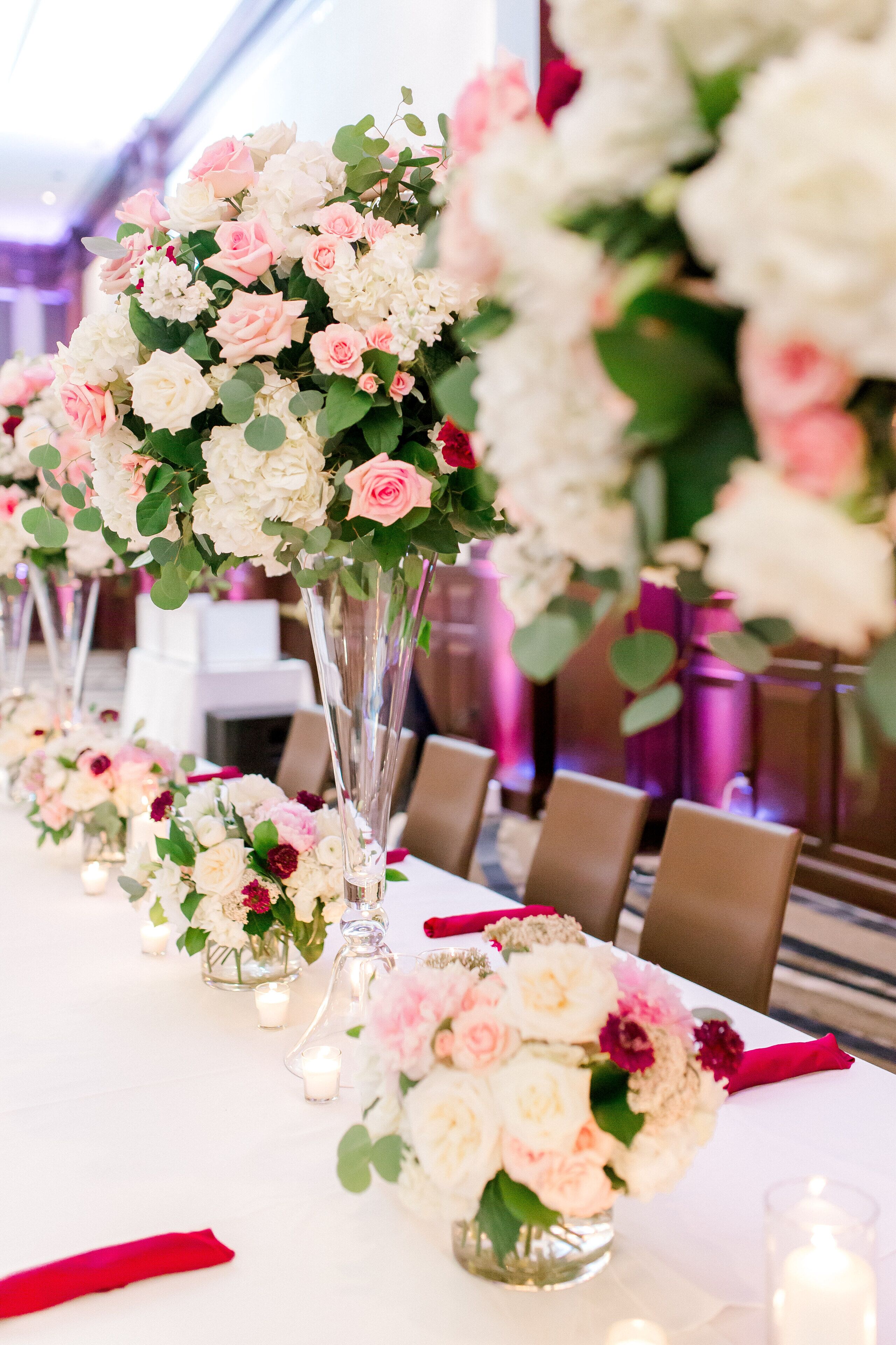 A long table with floral centerpieces and candles.