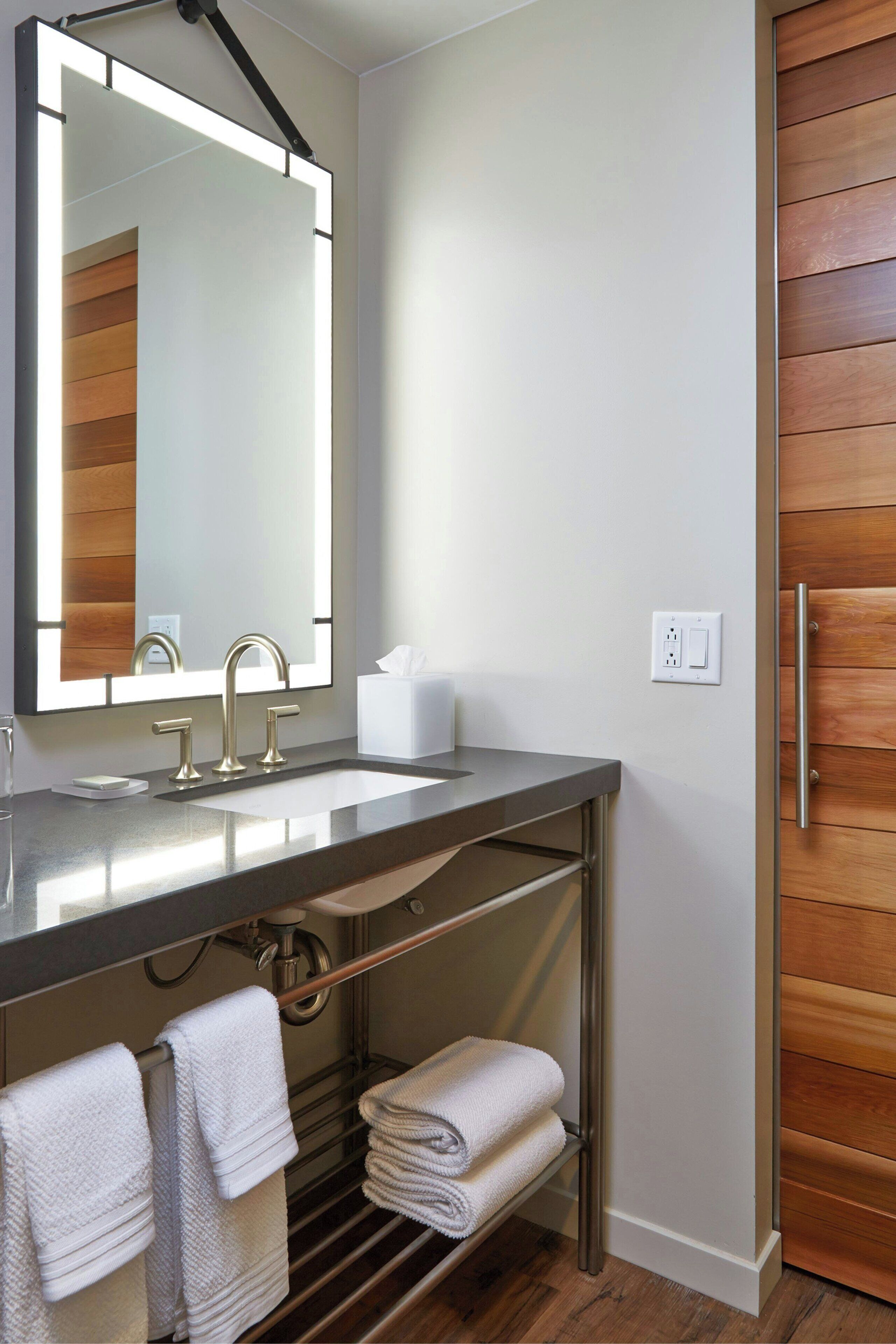 A modern bathroom with a large mirror, a sink, and a towel rack.