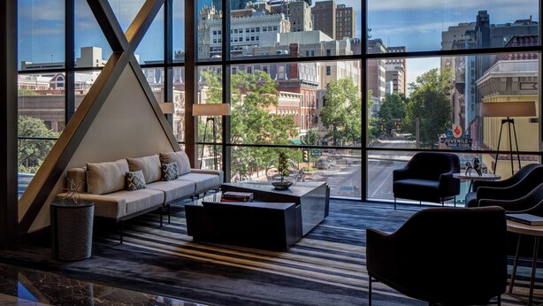 A modern living room with a large window, a sofa, a coffee table, and a lamp. - The Worthington Renaissance Fort Worth Hotel (Fort Worth)
