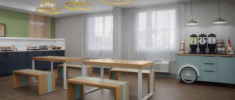 Un café moderno con mesas y bancos de madera, amplios ventanales con cortinas ligeras y una barra con diversas bebidas y aperitivos.