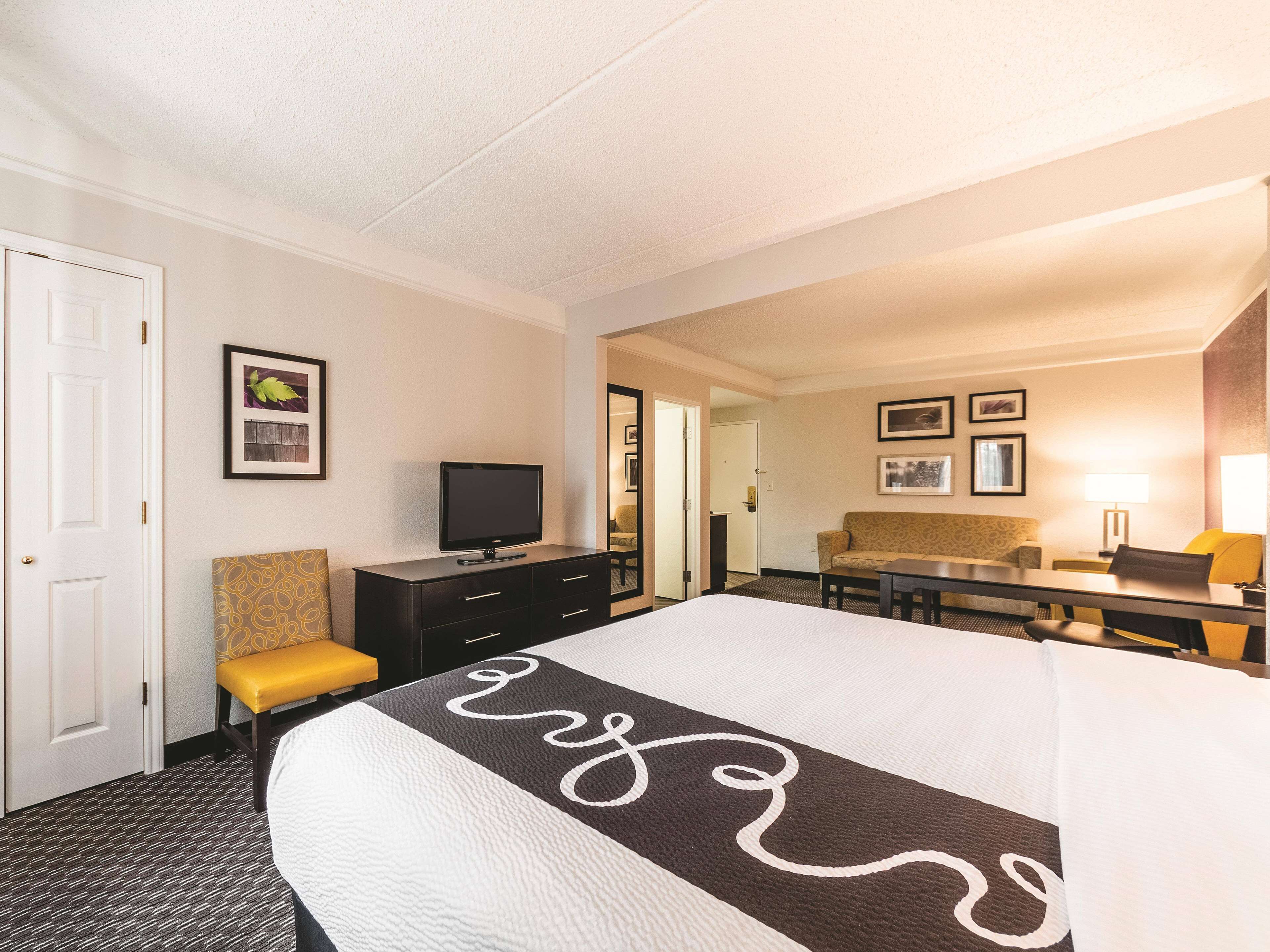 Une chambre d’hôtel équipée d’un lit, d’une télévision, d’un bureau, d’une chaise et d’un canapé.