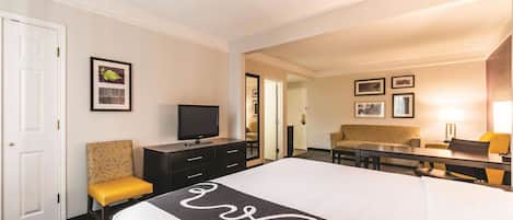 Una habitación de hotel con cama, televisor, escritorio, silla y sofá.
