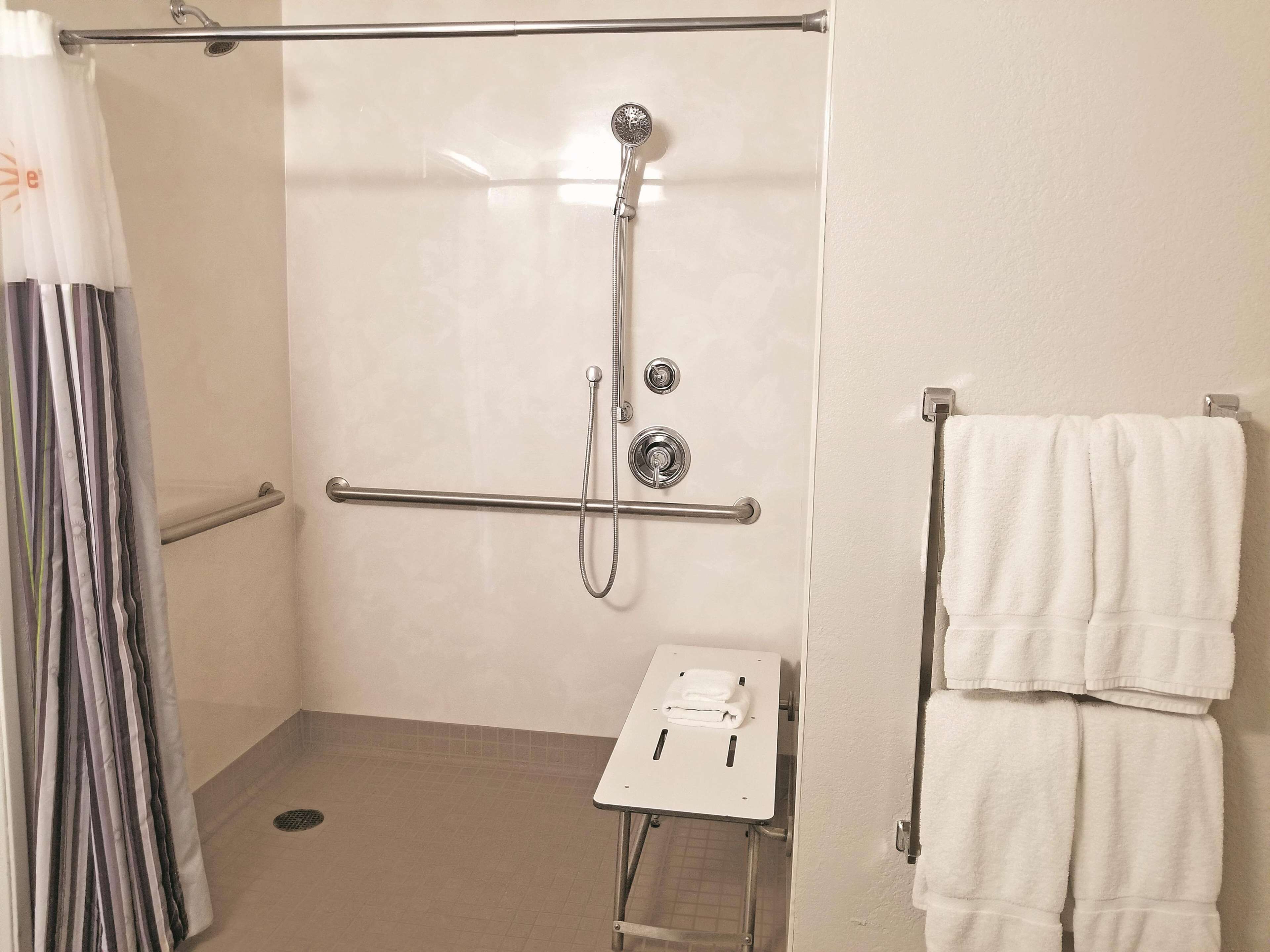A shower area with a grab bar, a towel rack, and a small table with a towel.