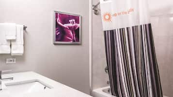 Um banheiro com cortina de chuveiro, um quadro na parede e uma toalha branca pendurada em um porta-toalhas.