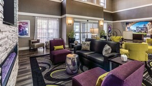A spacious lobby with a high ceiling, large windows, and a mix of seating areas including sofas and armchairs. - La Quinta Inn & Suites by Wyndham San Antonio Downtown (San Antonio)